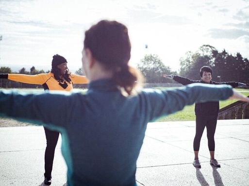 A group of three women stretching in a park